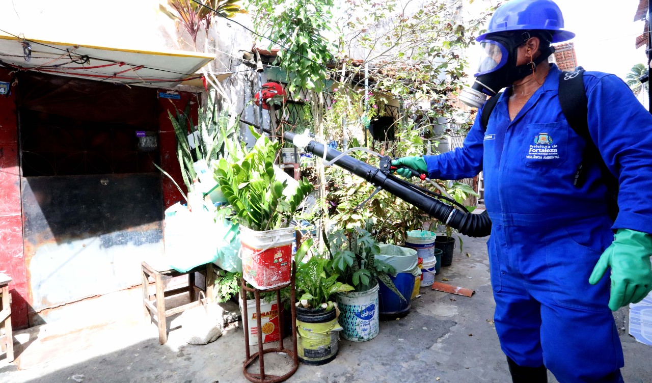 agente de endemia passando o fumacê num quintal